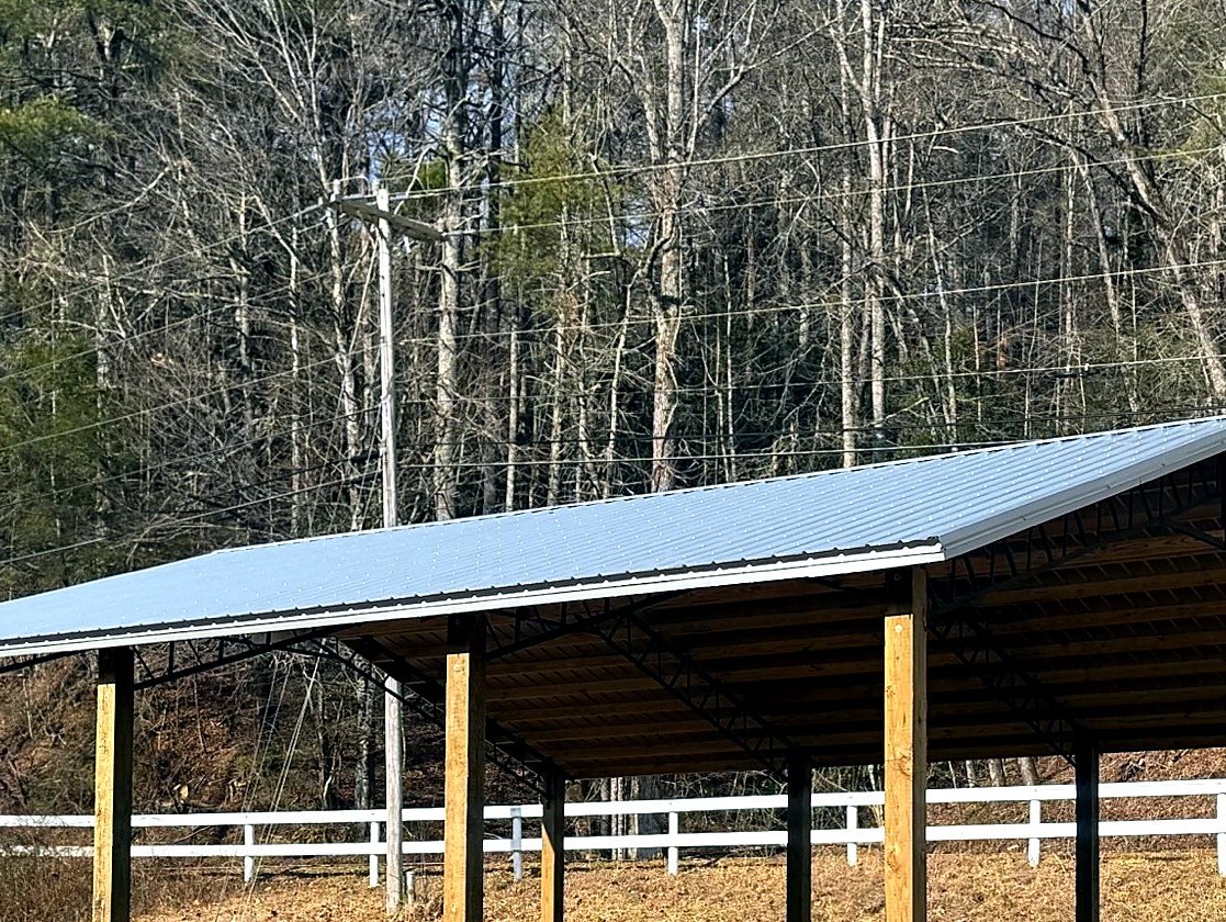 Three-quarter view of run-in shelter showing steel trusses under the metal roof