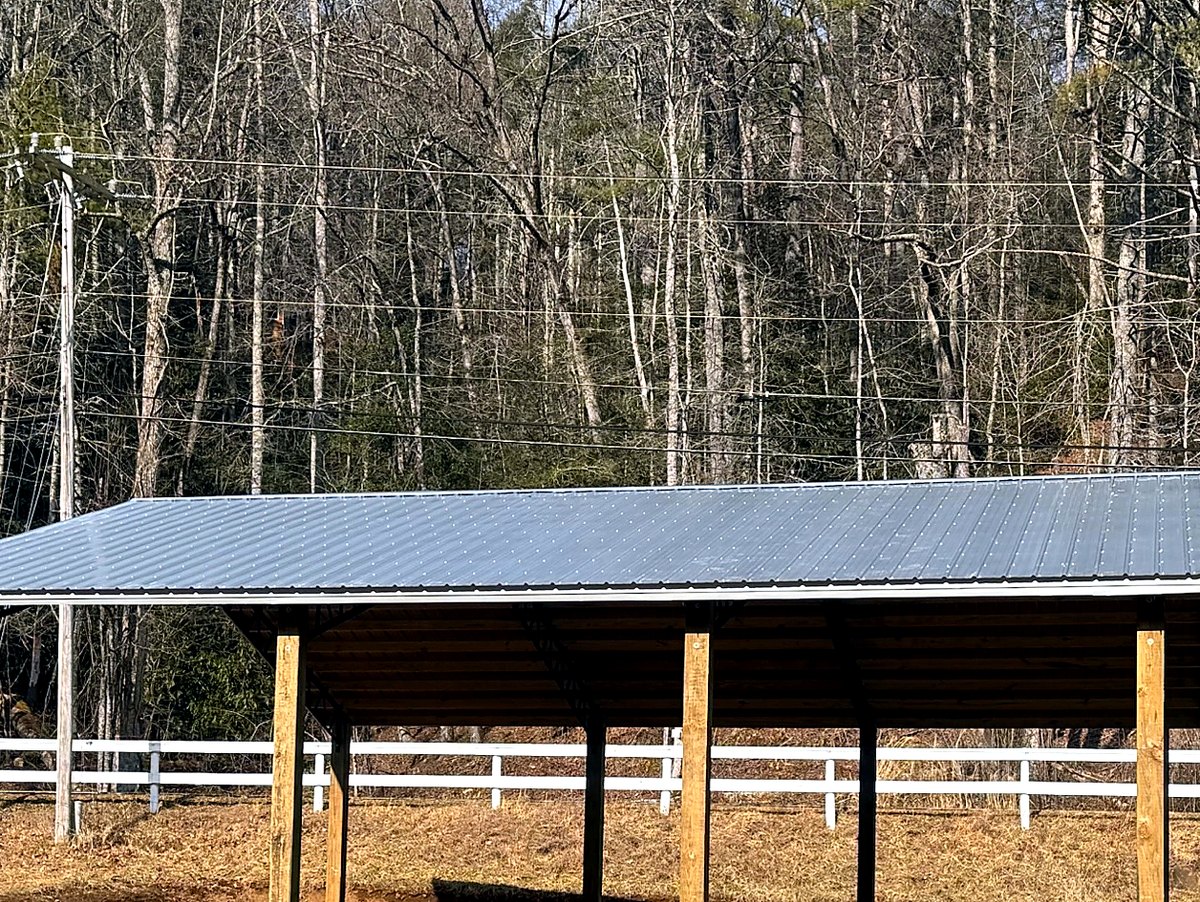 Side profile of an open-sided hay barn with metal roof and timber posts